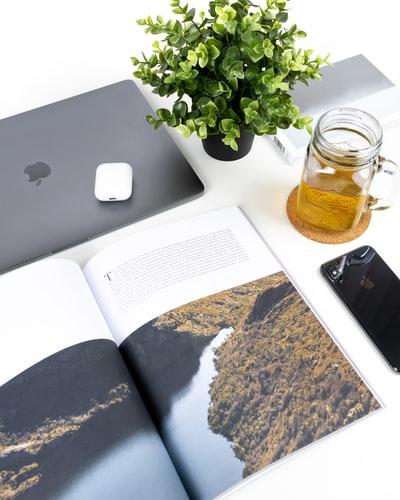 半空的透明玻璃罐green-leafed植物旁边,MacBook和空间灰色iPhone X
